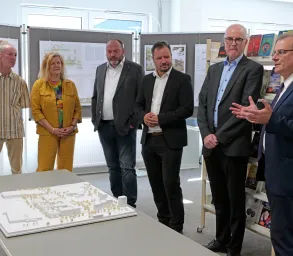 Gruppe Menschen stehen um Modell Schulzentrum